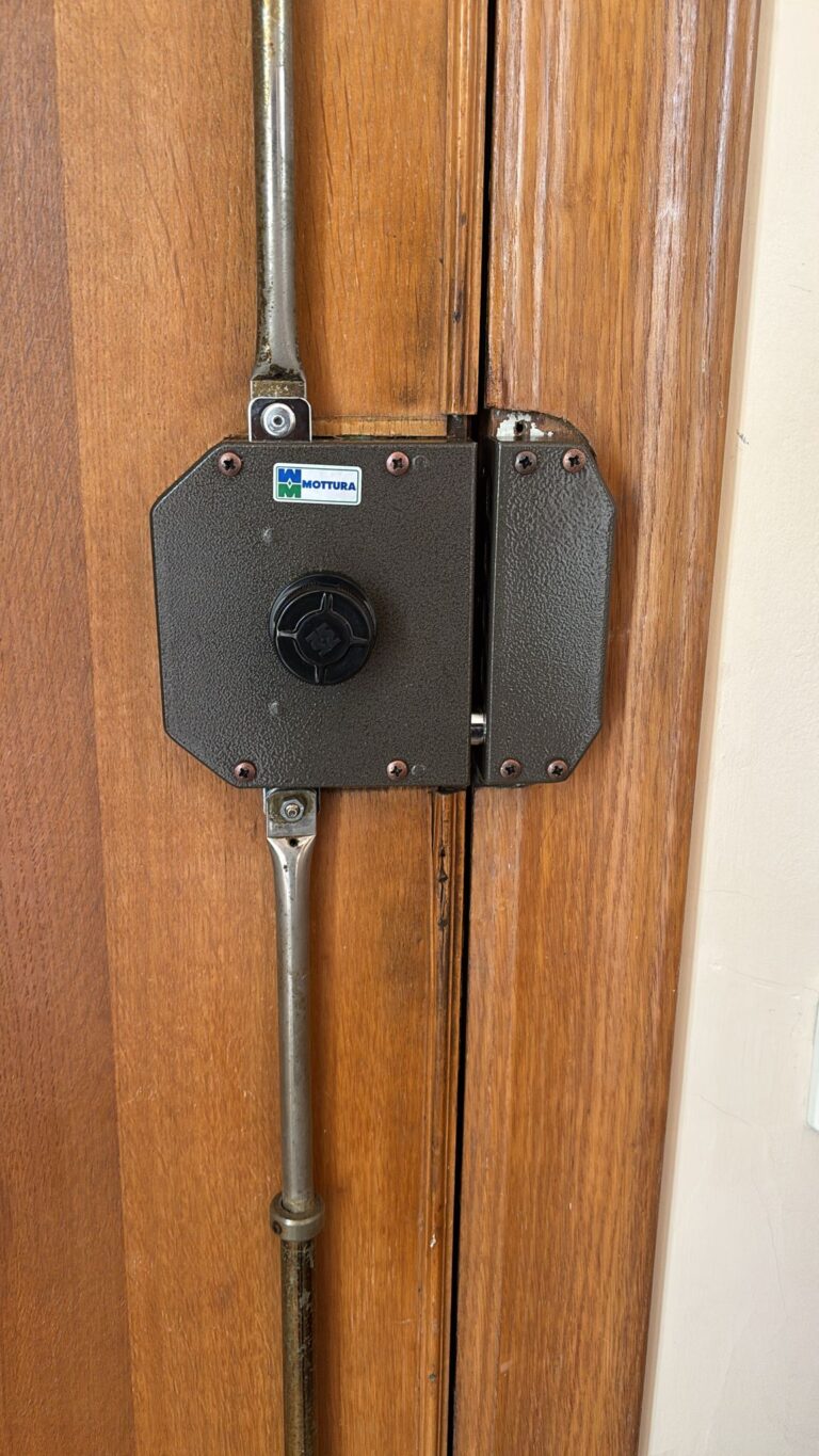 Cerradura de seguridad de sobreponer Mottura con varillas de anclaje superior e inferior instalada en puerta de madera