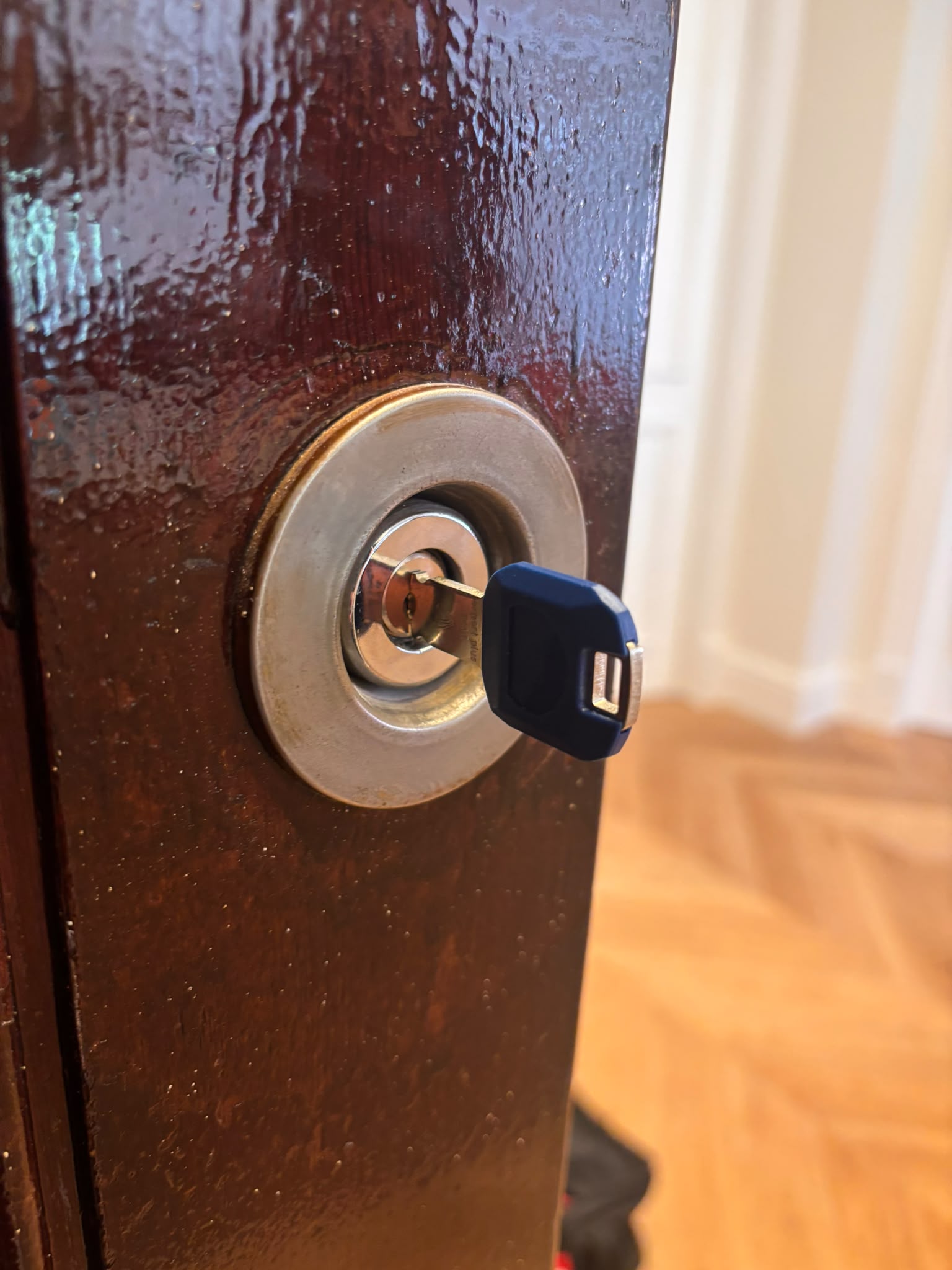 Llave azul insertada en bombín de puerta marrón